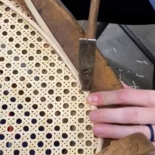 A Caner finishes a mat caned chair seat with a binder - seat weaving and chair caning
