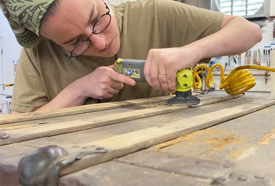 Craftsperson sands an antique trunk 565-1