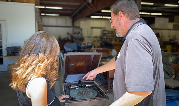 A client and Restoration Consultant Spencer Mayton look over a phonograph for restoration